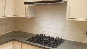 A kitchen with white cabinets, a gas stove, and a stainless steel range hood.
