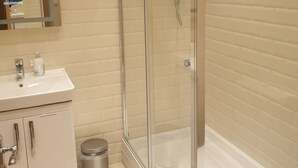A modern bathroom with a glass-enclosed shower, a white sink, and a mirror.
