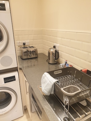 Enjoy meal preparation and laundry in this compact kitchenette with washing machine, toaster, and kettle.