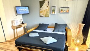 A modern hotel room with a bed, bedside tables, a TV, artwork, and a decorative vase. - Studio 5 mn des Plages (Schoelcher)