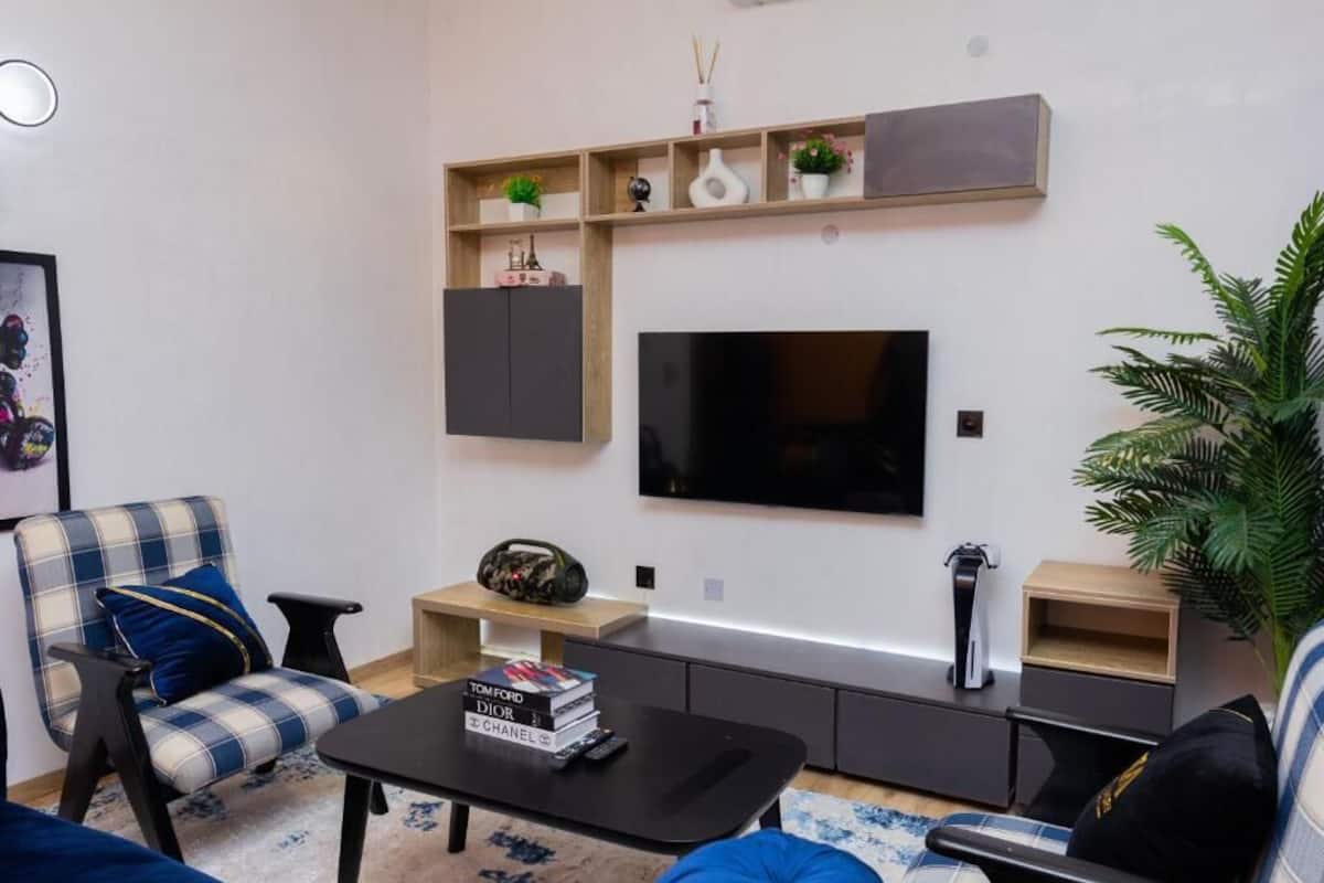 Una sala de estar moderna con una televisión de pantalla plana, un sofá, una mesa de centro y una estantería.