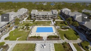 Vista aérea de una zona residencial con piscina central, céspedes cuidados y senderos.