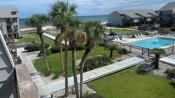 Un resort con piscina, palmeras y vistas al océano.