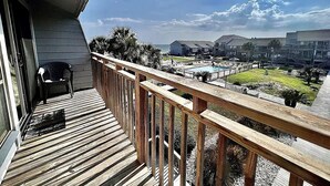 Una terraza de madera con vista a una piscina y edificios al fondo.