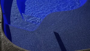 A swimming pool with a blue tint, surrounded by a concrete deck and a wooden fence. - Sea Hag-Heart of Carolina Beach-Private Inground Saltwater Pool (Carolina Beach)