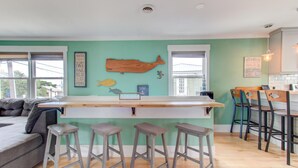 A kitchen with a bar area, wooden stools, and a fish-themed wall decoration. - Sea Hag-Heart of Carolina Beach-Private Inground Saltwater Pool (Carolina Beach)