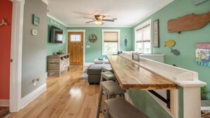 A kitchen with a wooden bar counter, stools, and a ceiling fan. - Sea Hag-Heart of Carolina Beach-Private Inground Saltwater Pool (Carolina Beach)