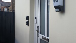 Eine Haustür mit Glasfenster, einem weißen Klingelknopf und einem Schild mit der Nummer 80 an der Wand.