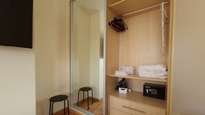 Ein begehbarer Kleiderschrank mit Holzböden, einem Spiegel und einem kleinen Hocker.
