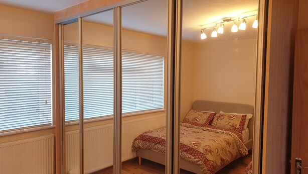 Ein Schlafzimmer mit einem Bett, einem Heizkörper und einem Fenster mit Jalousien.