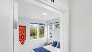 Ein Schlafzimmer mit Bett, Nachttisch, Lampe und Fenster mit Ausblick.