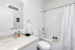 Bathroom features a white sink, toilet, and bathtub with a shower curtain.