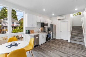 Enjoy meals in the dining area with a table and chairs, surrounded by large windows offering a view of the neighborhood.
