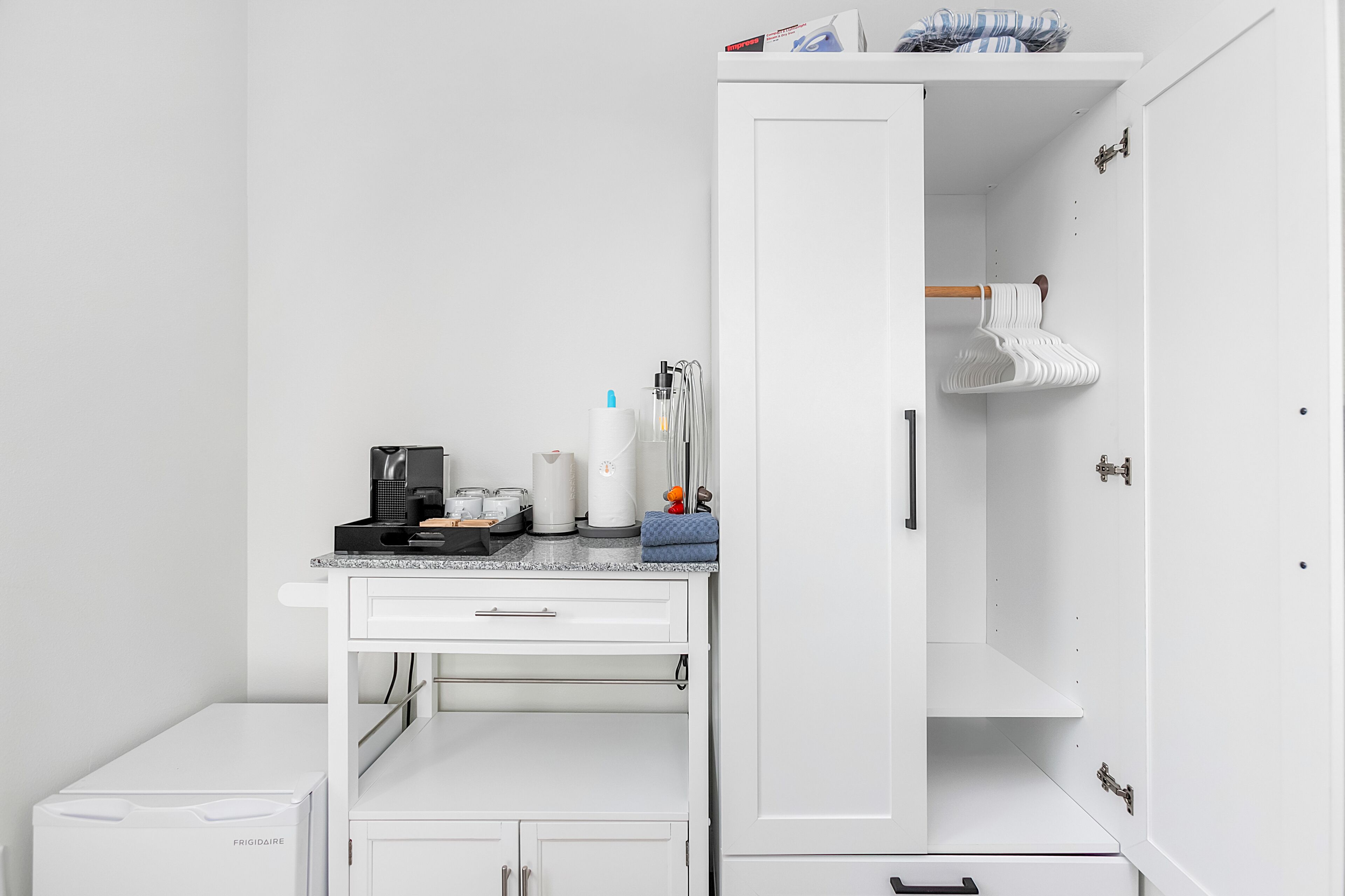 A compact kitchenette with a coffee maker, a kettle, and a small refrigerator.
