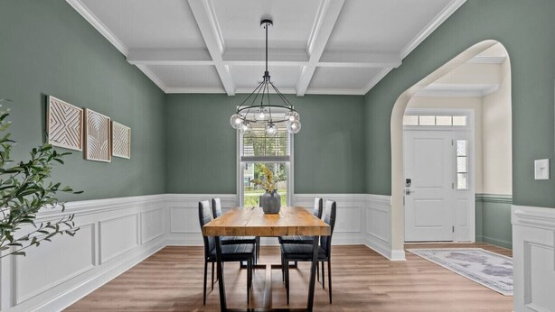 A dining room with a wooden table and chairs, a chandelier, and a view of the outdoors through a window. - Pickleball, Arcade & Poker Retreat Near Pinehurst! (Aberdeen)
