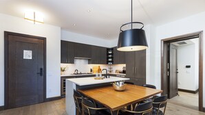 Una cocina moderna con armarios oscuros, una isla de madera y una lámpara colgante.