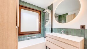 A modern bathroom with a freestanding bathtub, a large mirror, and a glass shower enclosure.