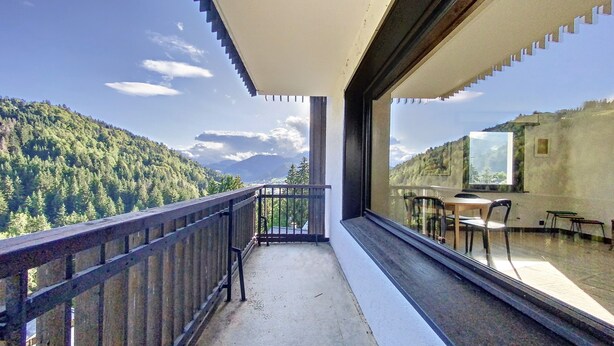 A balcony with a view of a forested mountain range.