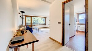 A hallway with a wooden table, a lamp, and a view of a balcony with a railing.