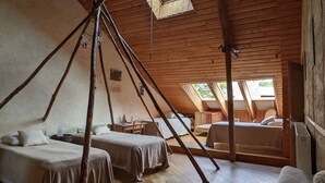 A rustic wooden room with two beds, a small table, and a chair. - L'HÔT'BERGE de Gannedel (La Chapelle-de-Brain)