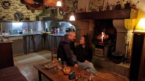 A cozy kitchen with a stone wall, a fireplace, and a dining table with glasses and bottles. - L'HÔT'BERGE de Gannedel (La Chapelle-de-Brain)