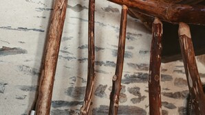 A wooden chair with a curved backrest and four legs, positioned against a textured wall with a stone-like pattern. - L'HÔT'BERGE de Gannedel (La Chapelle-de-Brain)