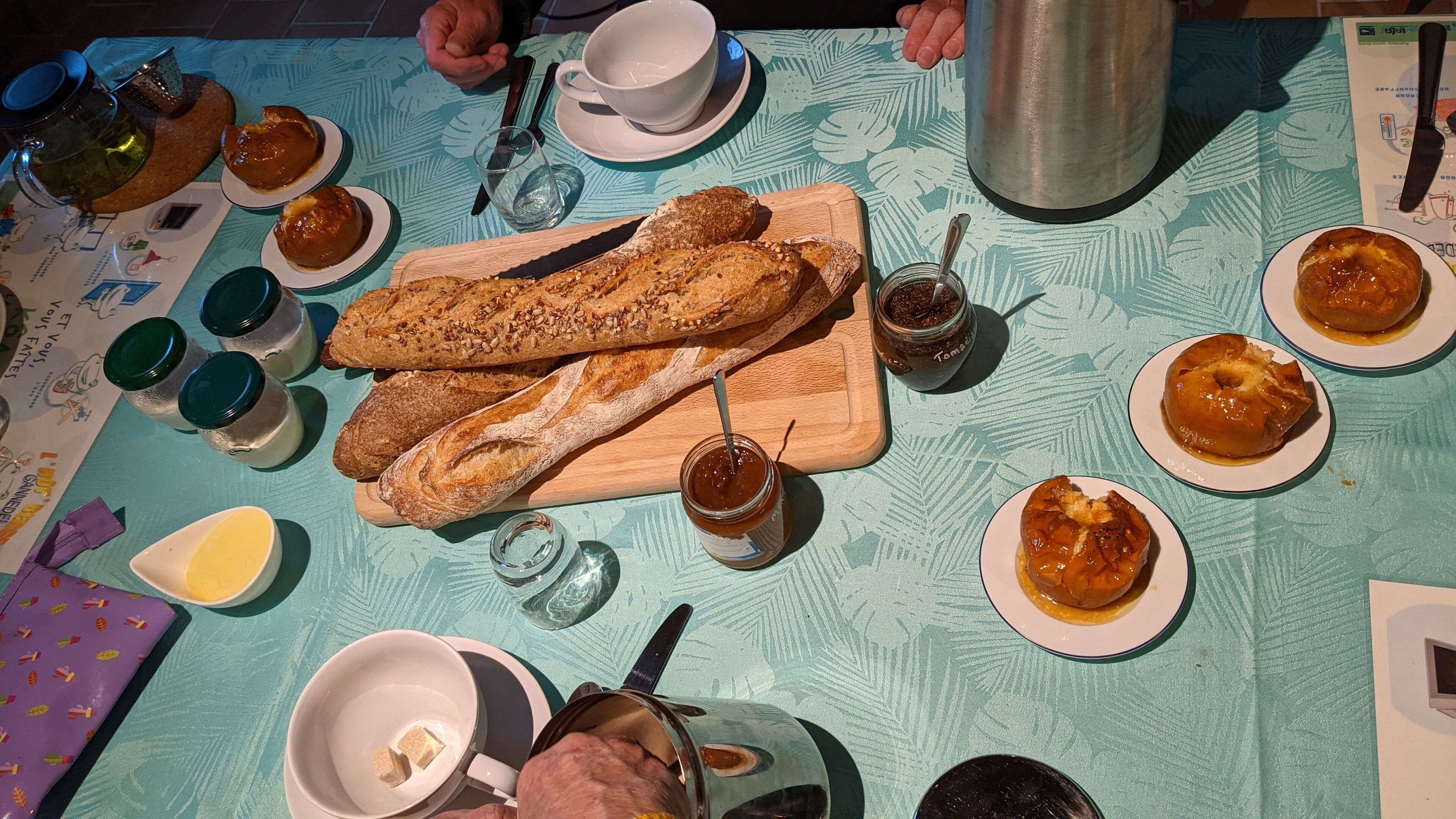 Une table dressée avec du pain, de la confiture et un thermos.