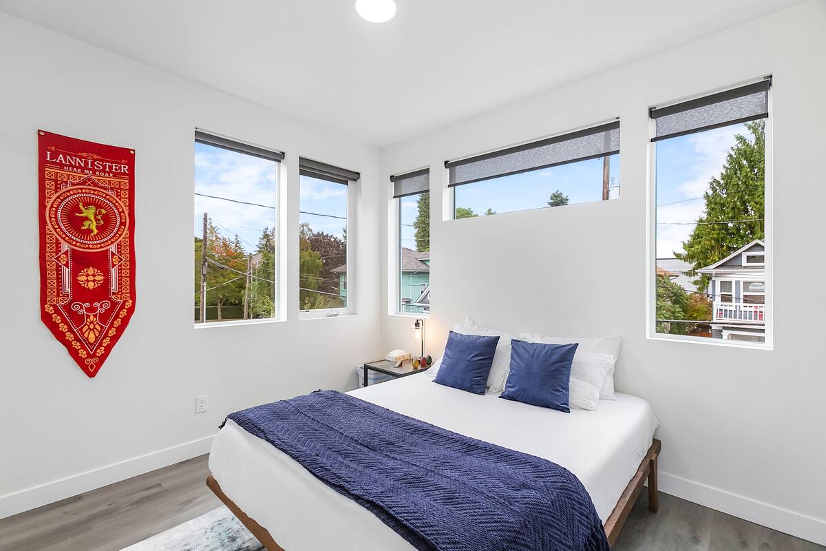A bedroom with a large bed, a nightstand, and a red banner on the wall.