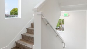 A staircase with wooden steps and white walls, leading to an exit. - The Golden Lion Sweet Suite (Seattle)