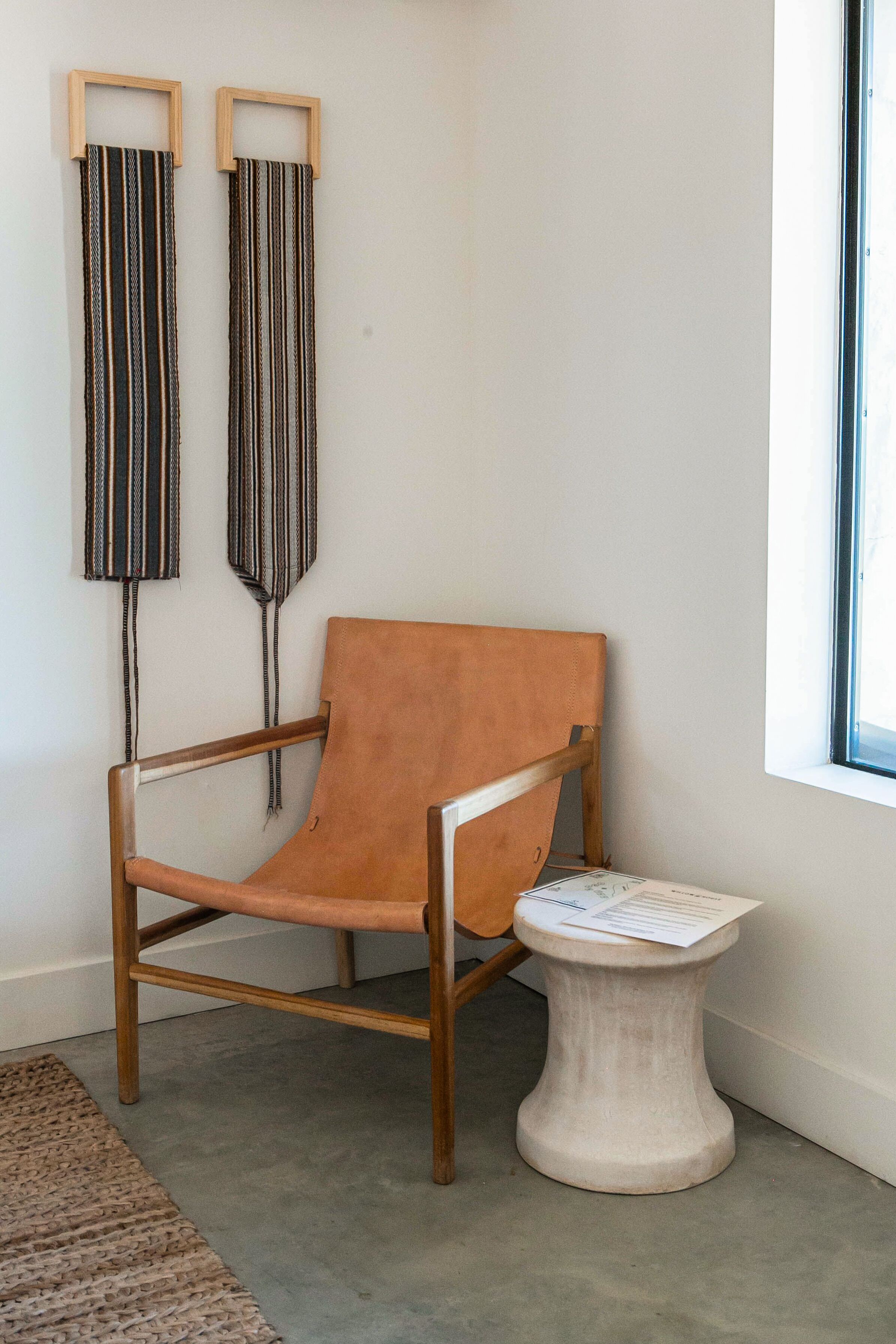 Une pièce d’angle avec une chaise en bois, une petite table blanche et deux décorations murales à rayures.