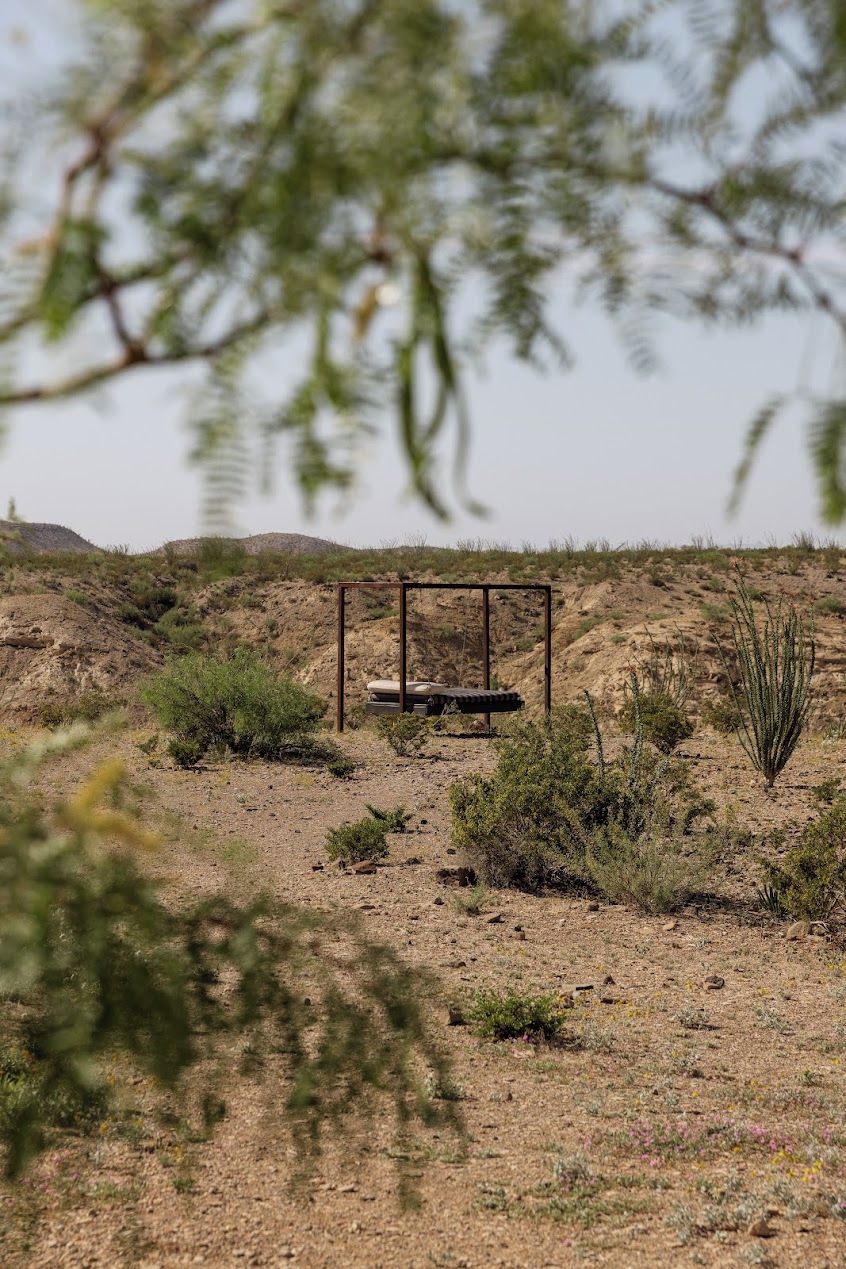 A desert landscape with sparse vegetation, a metal structure, and a clear sky.