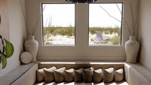 A modern living room with a large window, a sofa, a coffee table, and decorative vases. - Willow House (Terlingua)