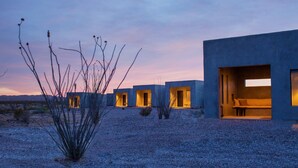 A modern building with multiple rooms, each with an open doorway and a window. - Willow House (Terlingua)