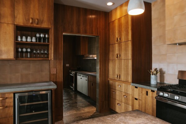 A modern kitchen with wooden cabinets, stainless steel appliances, and a marble countertop. - Willow House (Terlingua)