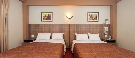 Habitación de hotel con dos camas, cabecero de madera, obra de arte en la pared, mesitas de noche y un teléfono.