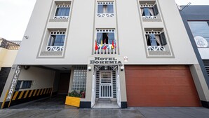 Ein Hotel mit moderner Fassade, einem zentralen Eingang mit Metallgitter und mehreren fensterlosen Vorhängen.