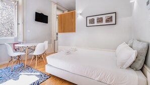 Een moderne hotelkamer met een bed, een bureau met stoelen, een raam en een tv aan de muur.
