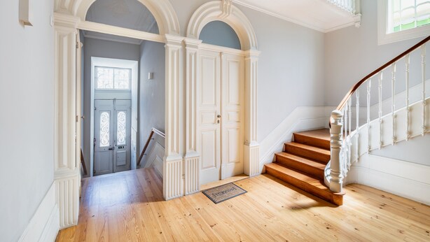 Een statige trap met witte balustrades die naar een verdieping leidt.