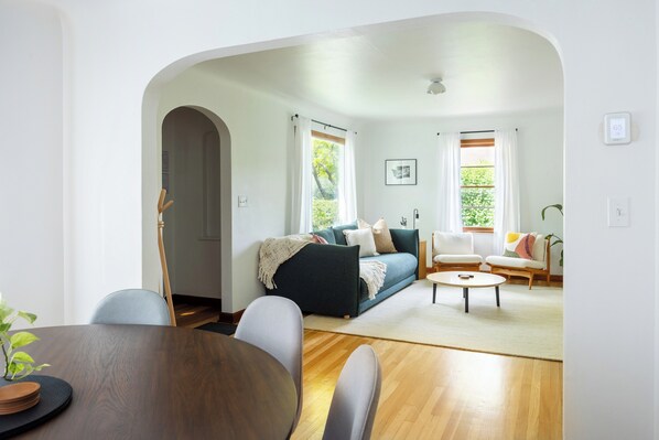 A modern living room with a sofa, chairs, a coffee table, and a dining table.