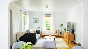 Ein Wohnzimmer mit einer Couch, zwei Sesseln, einem Couchtisch und einem Fernseher-Schrank.