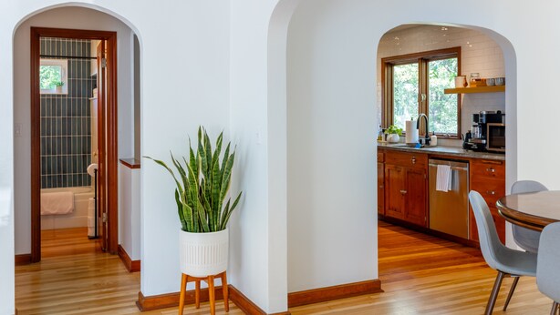 Eine moderne Küche mit Holzausstattung, ein Essbereich mit Tisch und Stühlen sowie ein Blumentopf.