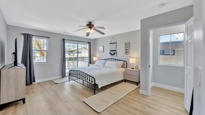 A bedroom with a bed, bedside tables, a ceiling fan, and a view of the outside. - Right By The Sand, Entire 3-Bedroom House In Belmont Shore (Long Beach)