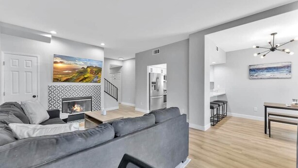 A modern living room with a gray sofa, a fireplace, and a dining area with a table and chairs. - Right By The Sand, Entire 3-Bedroom House In Belmont Shore (Long Beach)