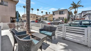 A patio with wicker furniture, a palm tree, and a white fence. - Right By The Sand, Entire 3-Bedroom House In Belmont Shore (Long Beach)