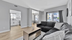 A modern living room with a grey sofa, a wooden coffee table, and a view of the outside. - Right By The Sand, Entire 3-Bedroom House In Belmont Shore (Long Beach)
