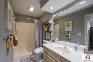 A modern bathroom with a bathtub, toilet, and sink. There is a shower curtain, a towel rack, and a mirror. - Fairways 11-3 (Branson)