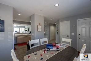 A dining area with a round table, white chairs, and a patriotic-themed table runner. - Fairways 11-3 (Branson)