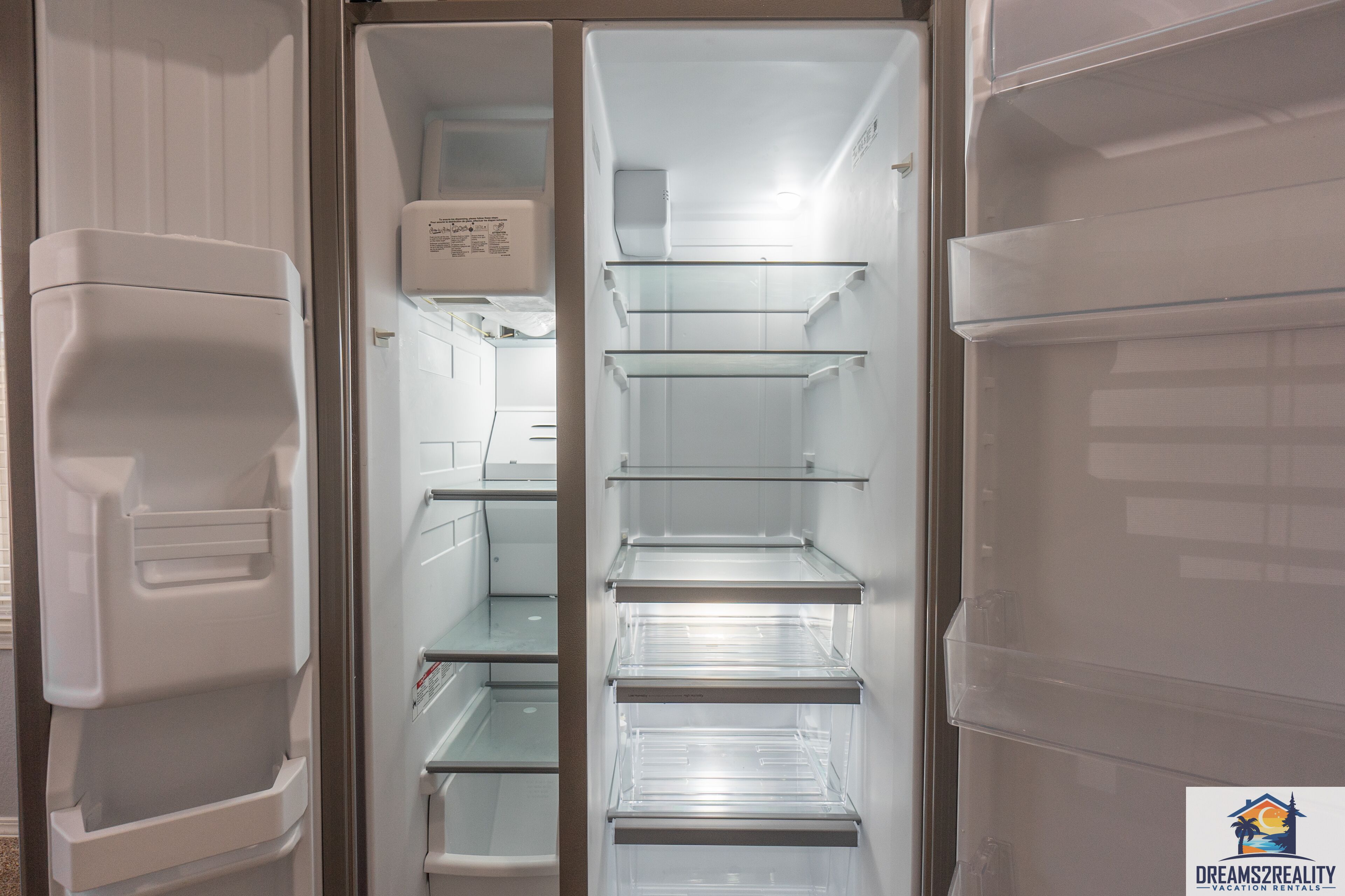 Interior moderno y vacío de un refrigerador con varios estantes y dispensador de agua.