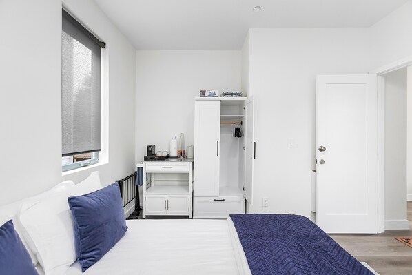 A bedroom with a bed, a desk, and a wardrobe.