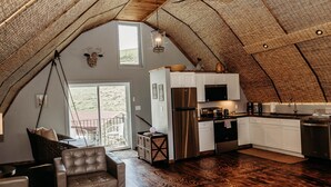Un loft acogedor con techo alto, una cocina con electrodomésticos modernos y una zona de estar con sillones de cuero.